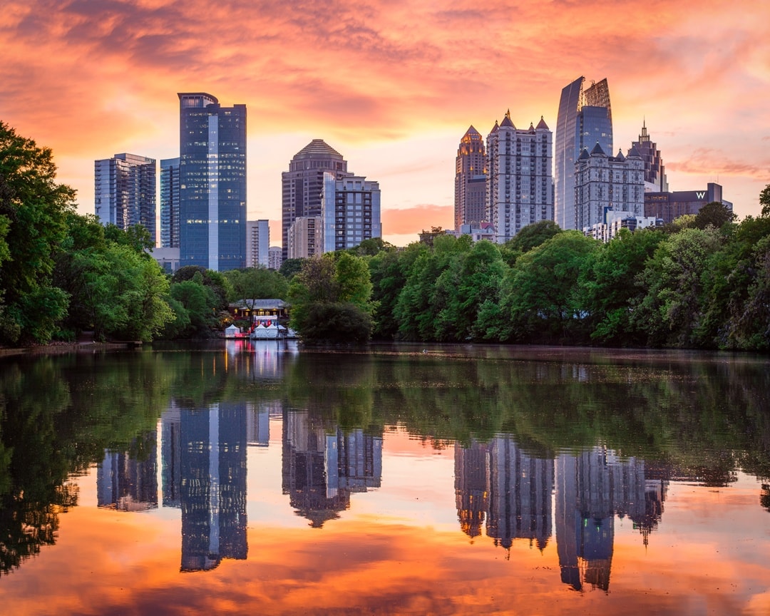 The Midtown skyline from Piedmont Park reflecting in the water of Clara Meer Lake at sunset