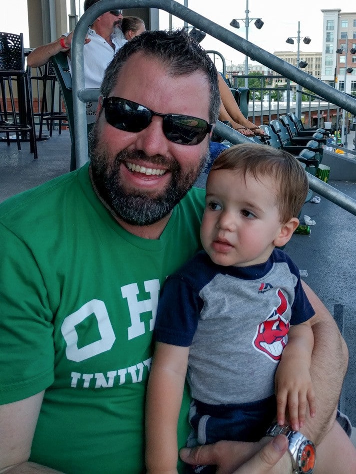 The Hungry Travel Daddy and Deacon at a minor league baseball game with our Baby Jogger City Tour Stroller stored neatly under our seat