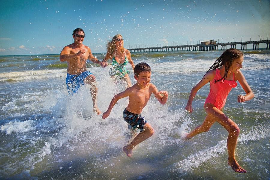 A family playing in the waves in Alabama's Gulf Shores with kids