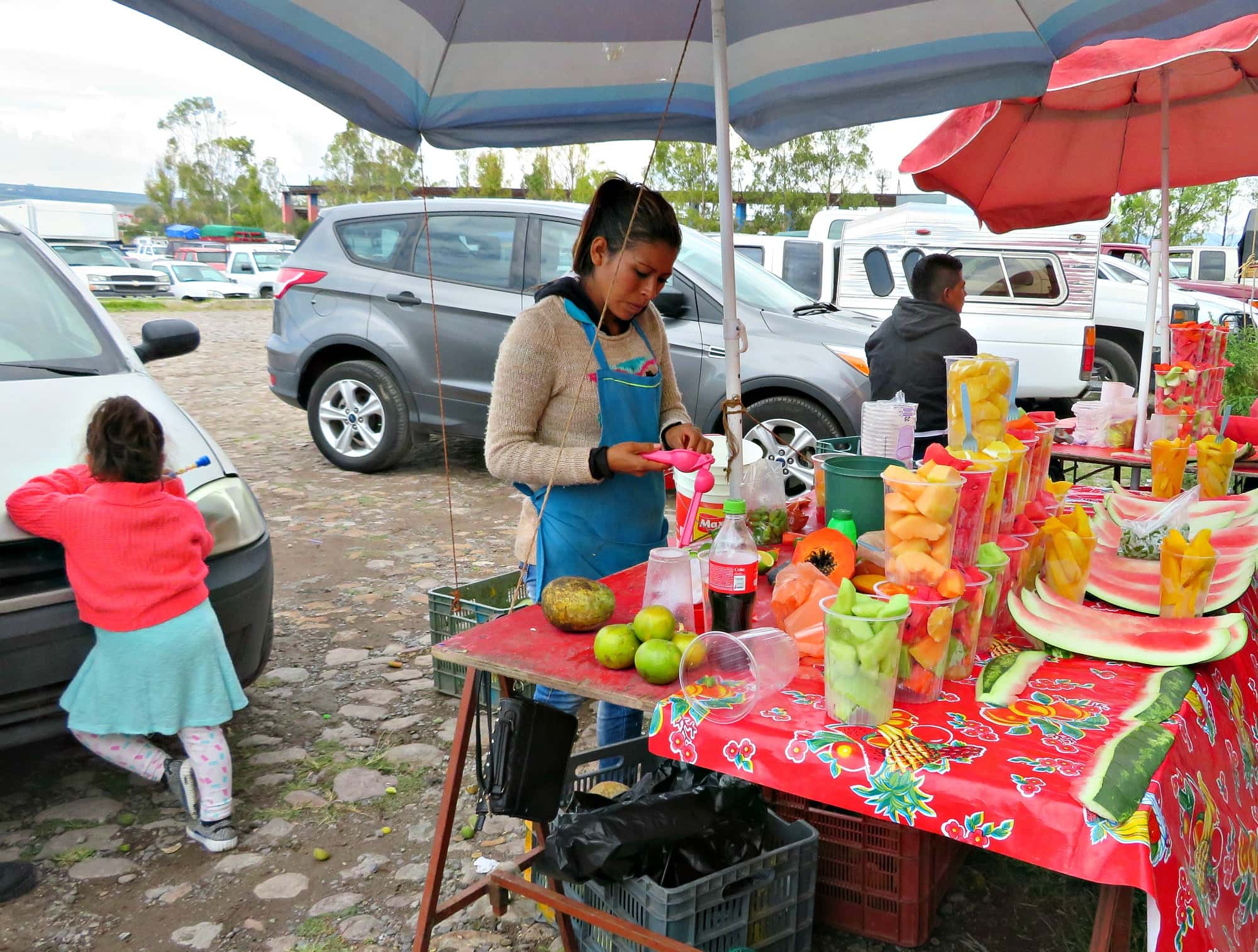 A vendor selling fresh fruits at Tuesday Market in San Miguel de Allende with kids