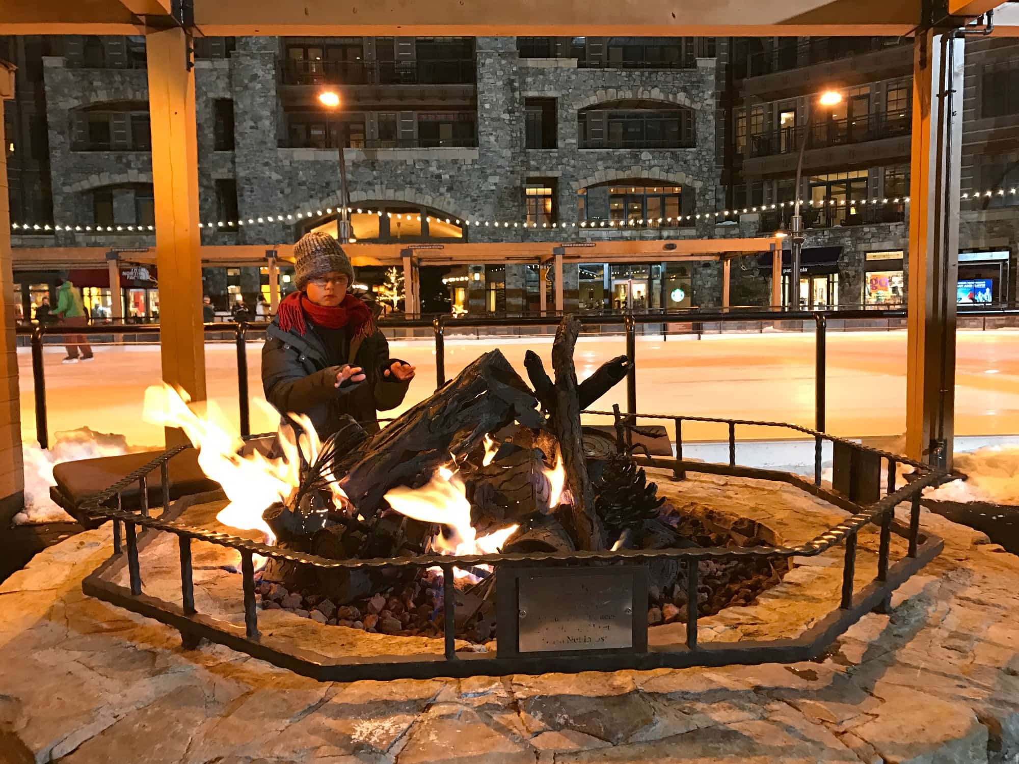 My son warming up by the fire at the ice rink in the Village at Northstar 