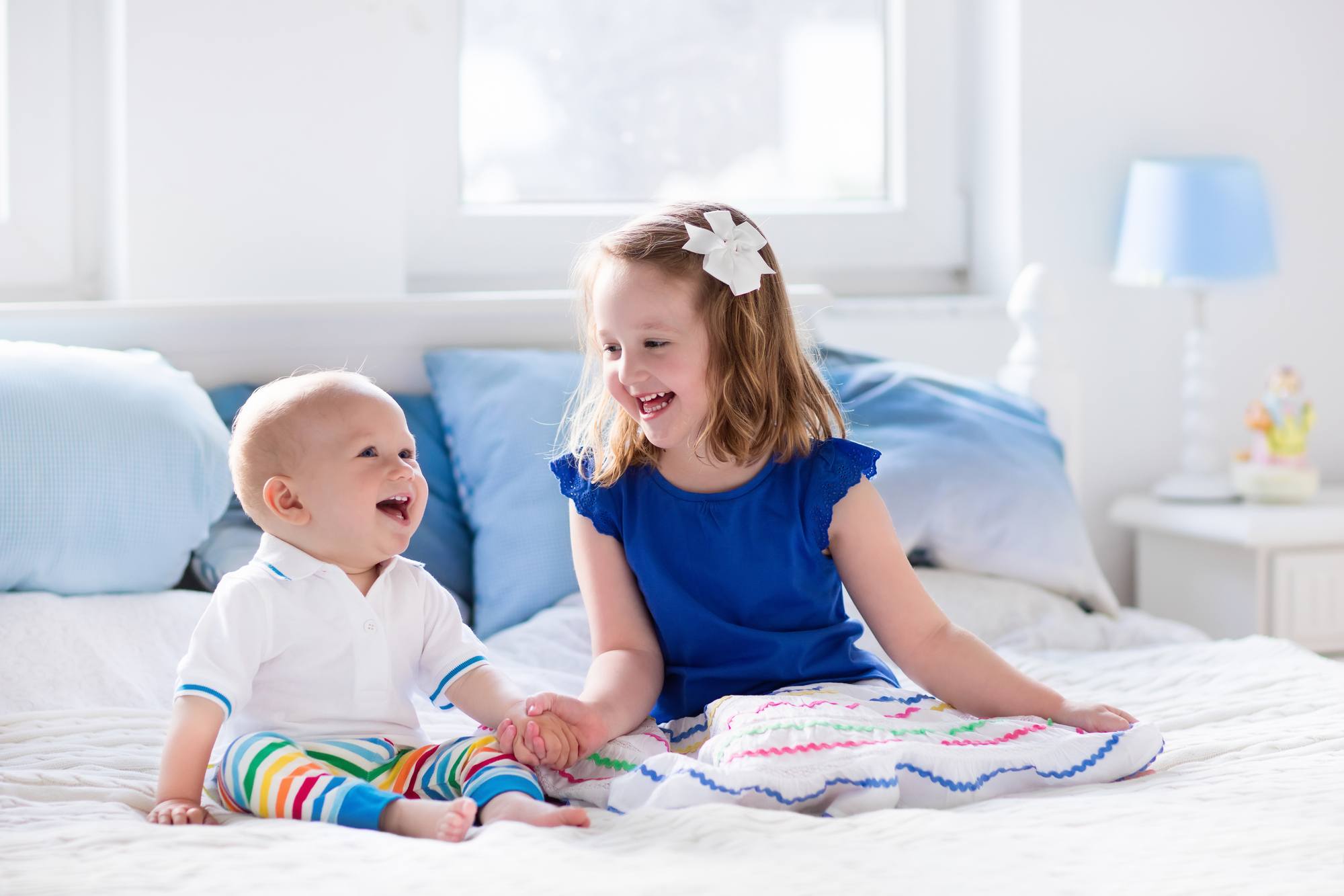 Baby and preschooler happy on a bed