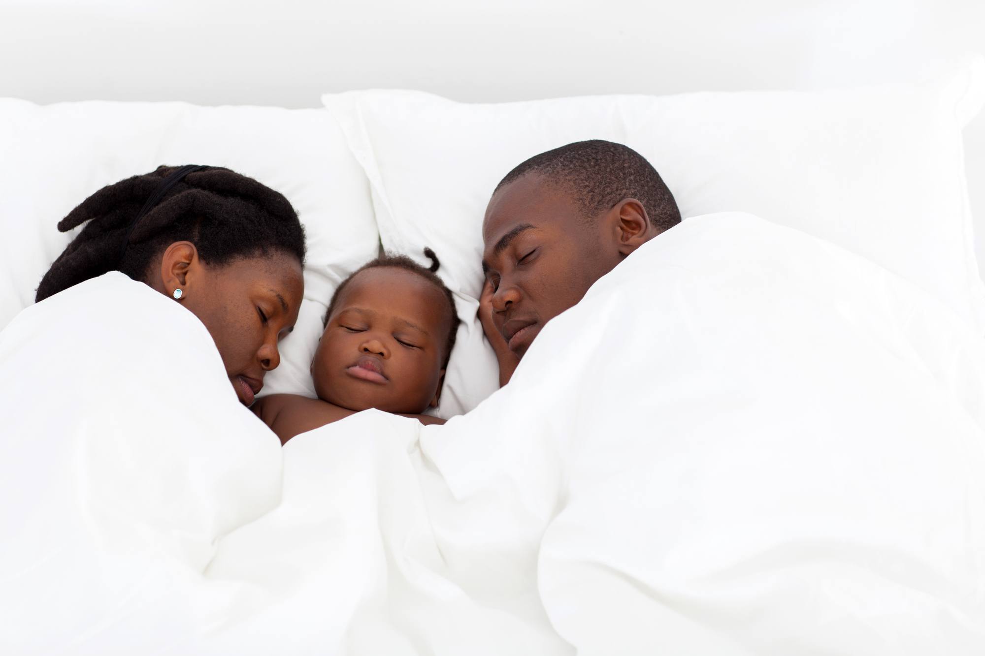 Parents and baby sleeping in bed together