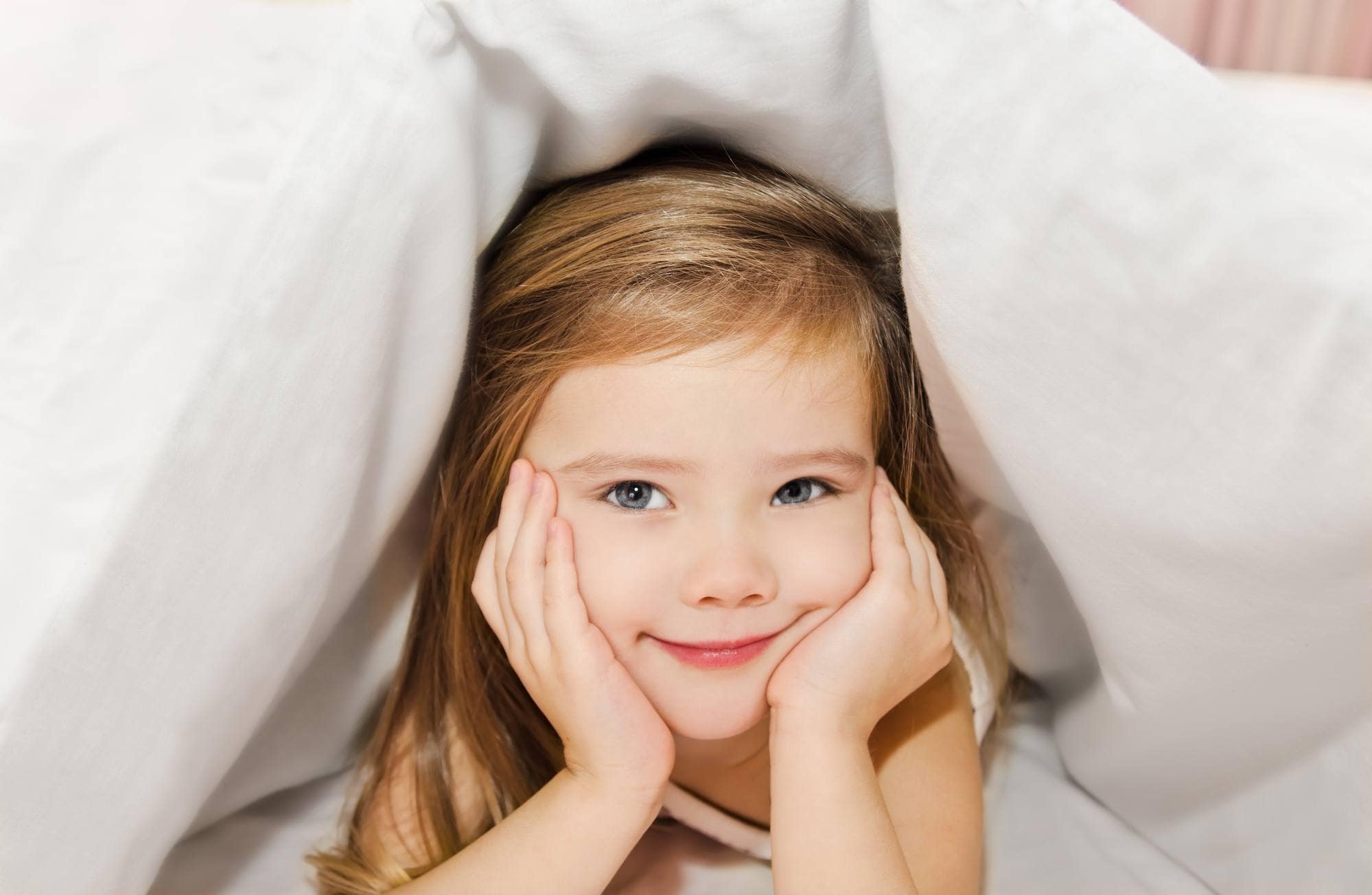 Well-rested child under covers on a bed