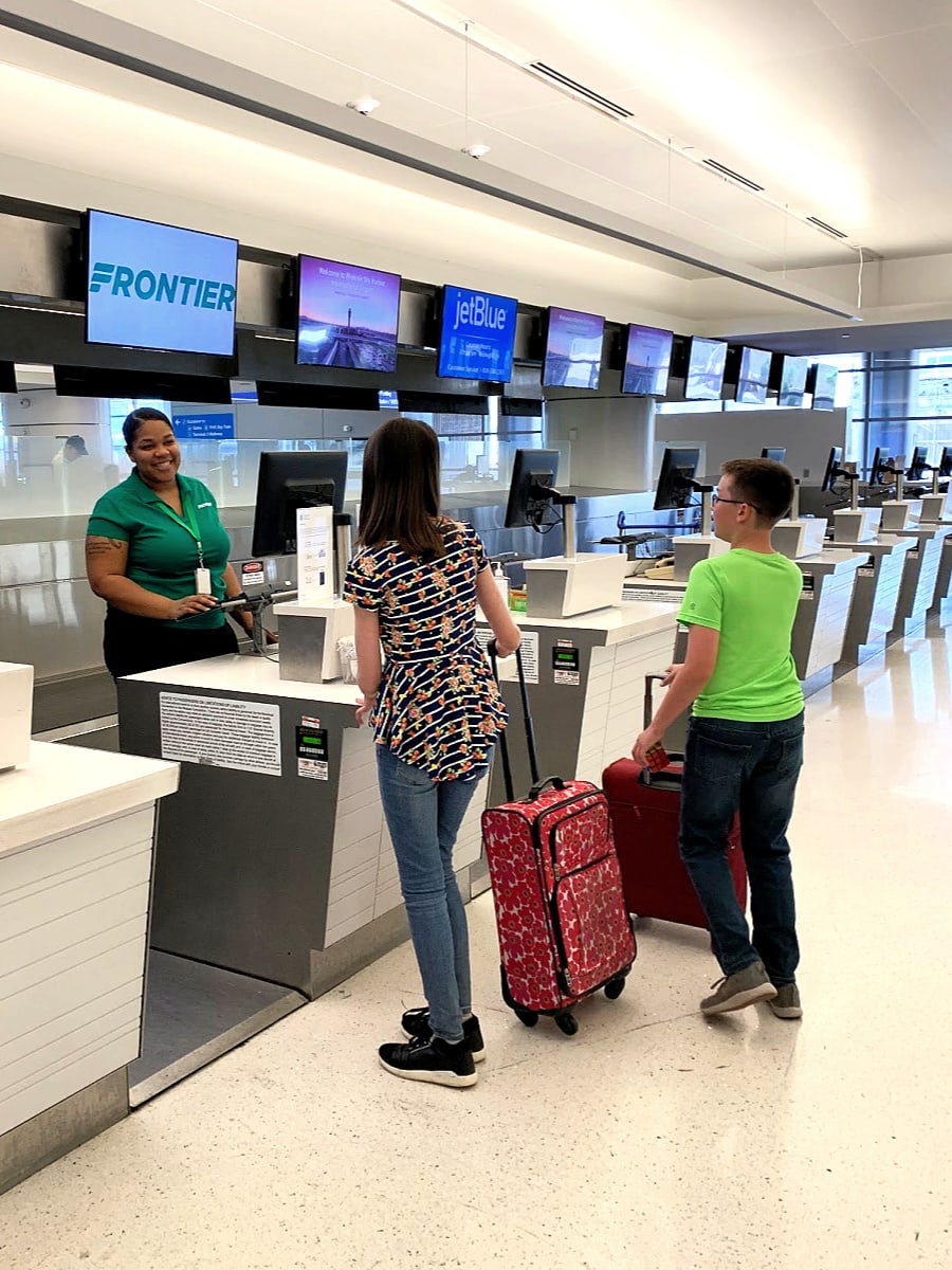 A friendly Frontier Airlines staff member assisting my kids at the airport