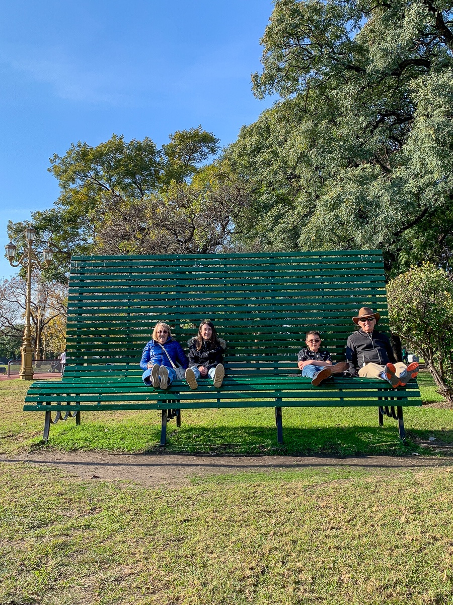 Kids sitting with grandma and grandpa on a huge park bench in Buenos Aires