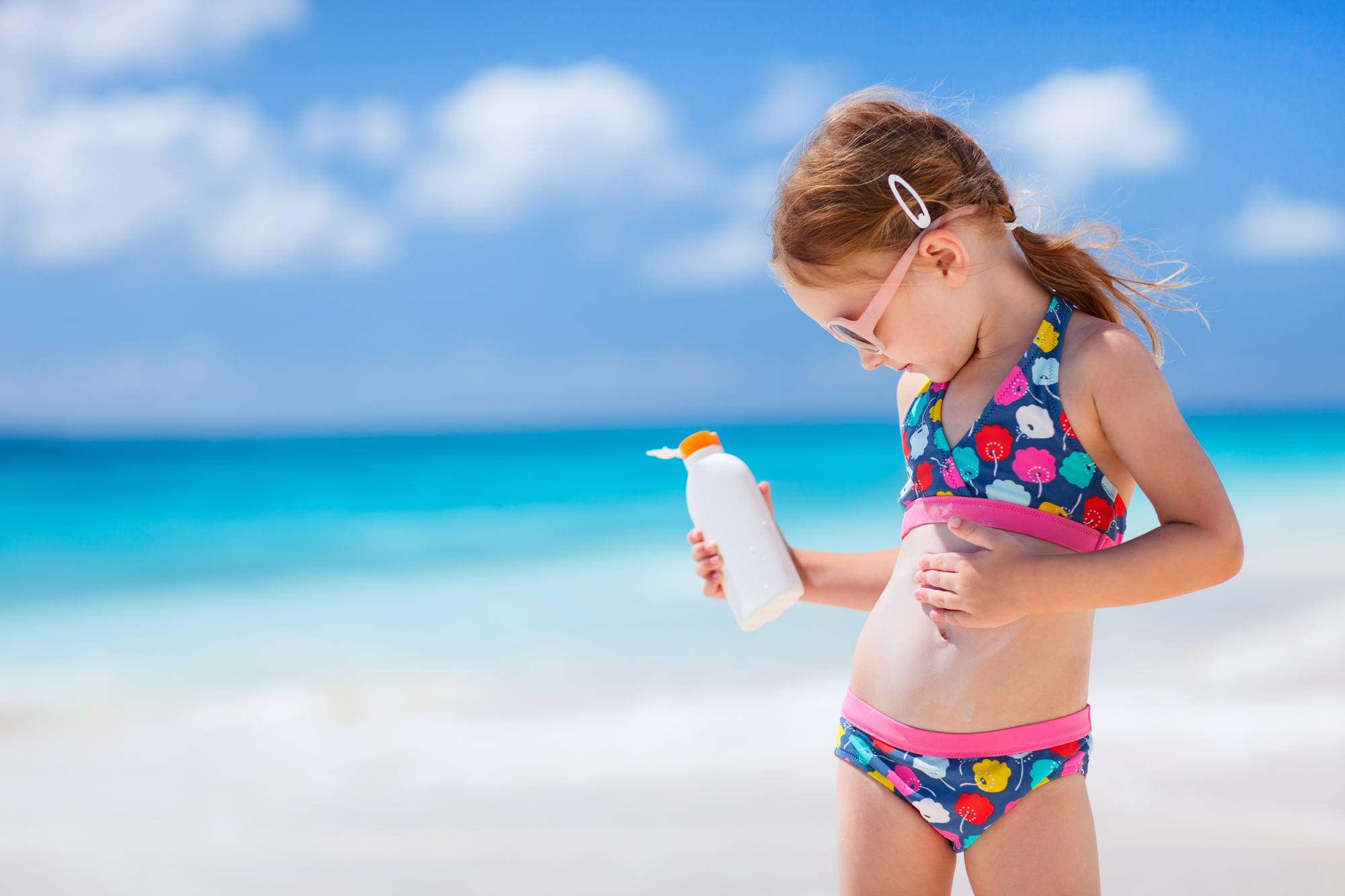 Child applying sunscreen on the beach