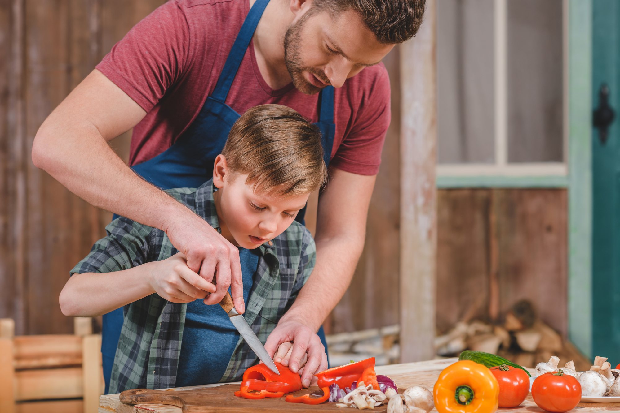 Dad grilling vegetables with son