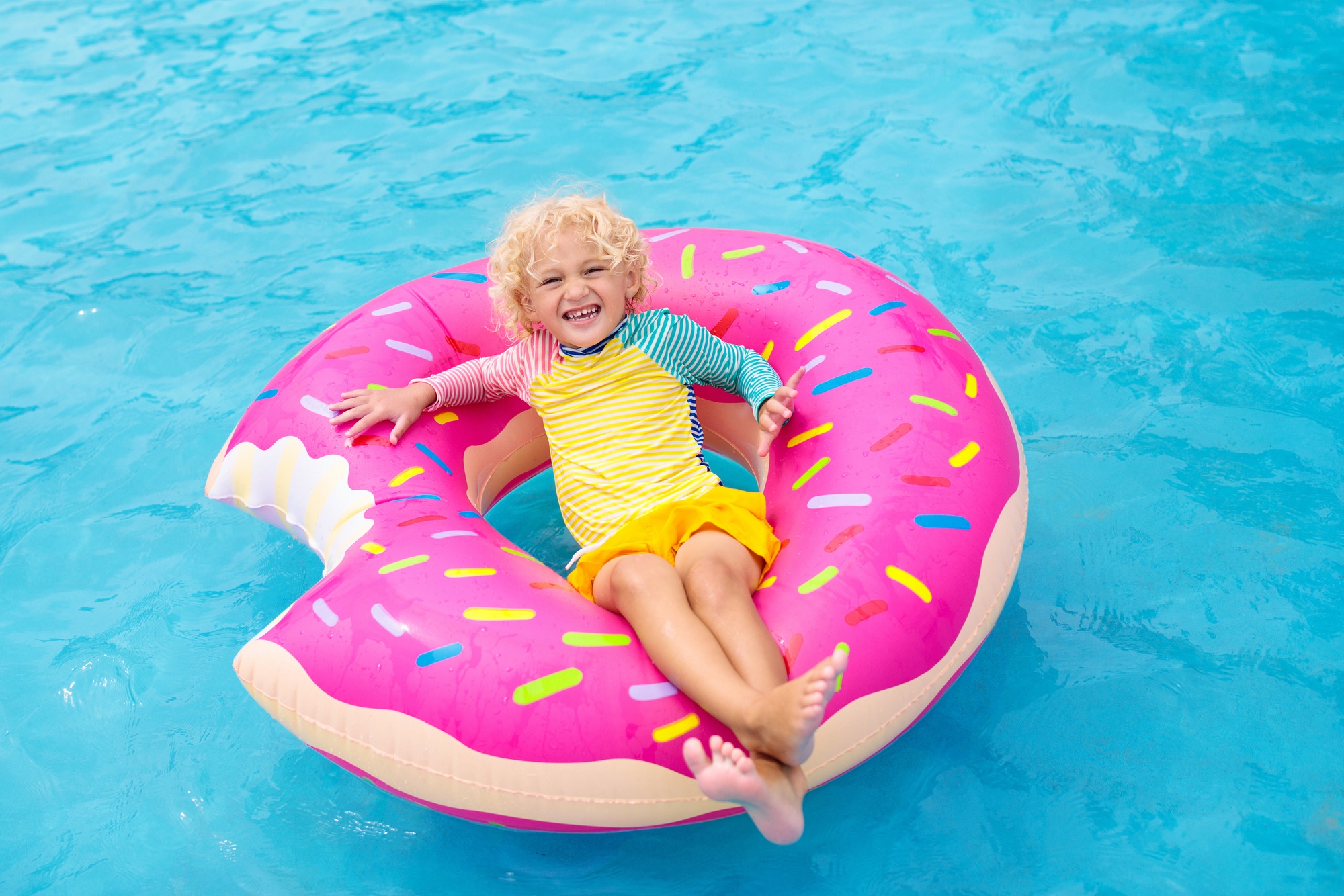 Child floating in donut pool toy