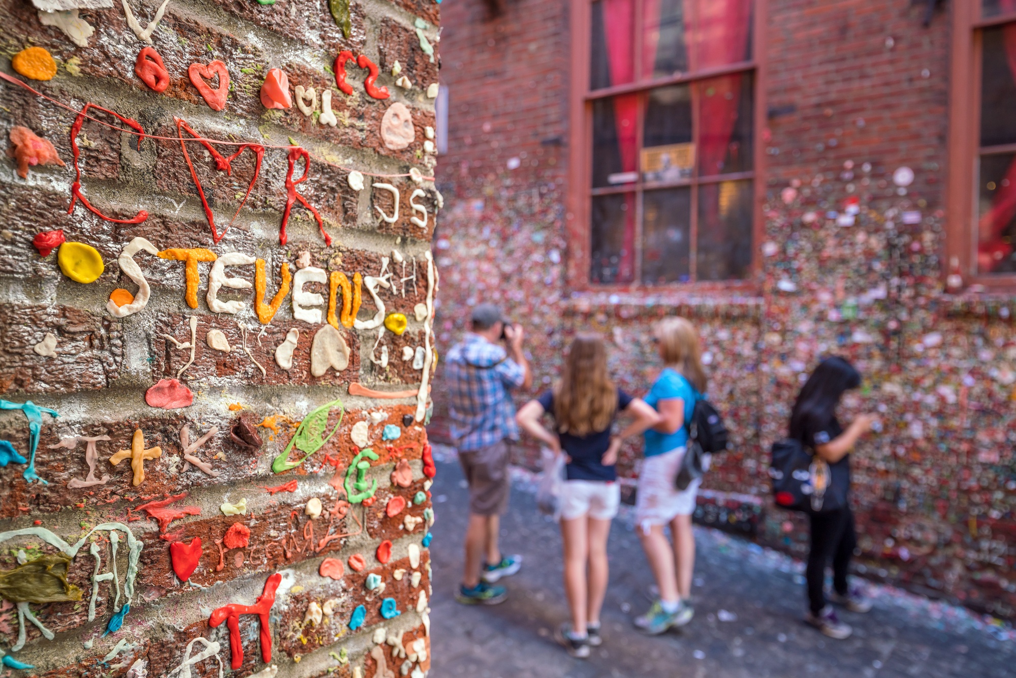 Family exploring the Market Theater Gum Wall in Seattle on vacation