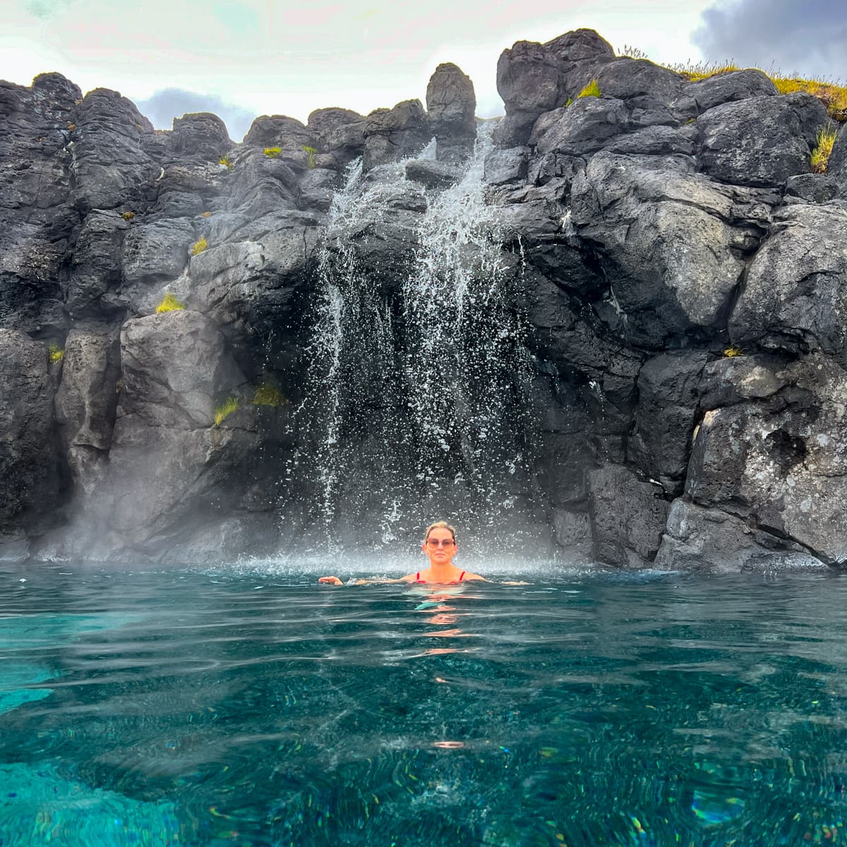 Swimming under a warm waterfall at Sky Lagoon