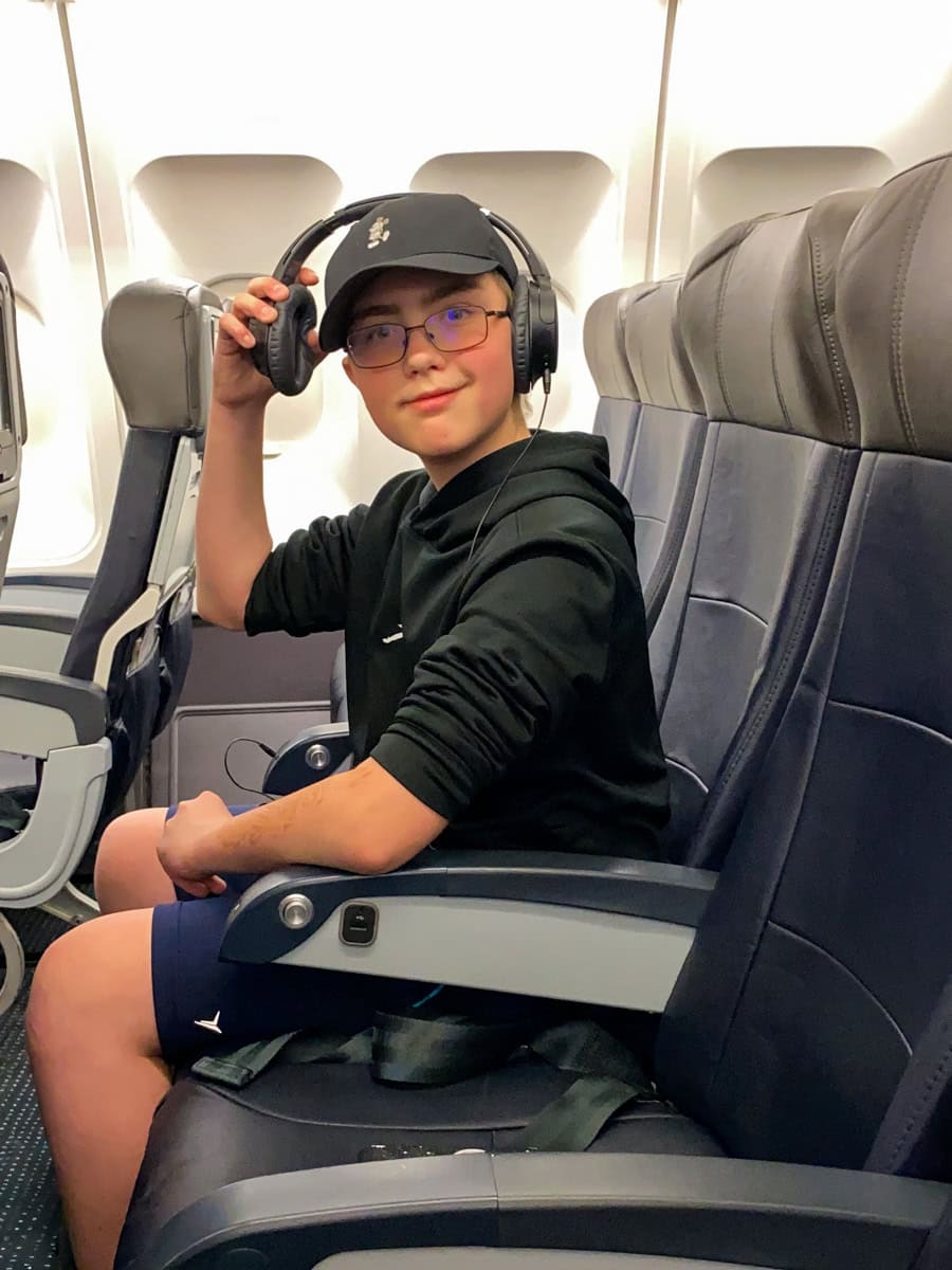 Child relaxing with headphones on airplane, using music to ease motion sickness symptoms